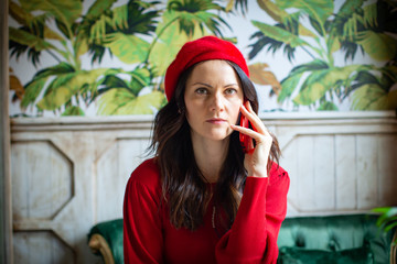 Fototapeta premium nice womani dress in red speaking on the phone with beret