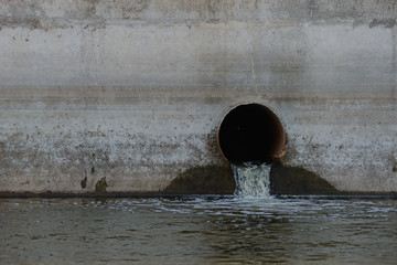 Sewer pipe in a concrete wall from which water flows into the reservoir