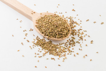 Anise seeds on wooden spoon on white background