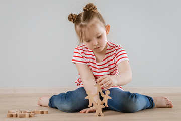 Naklejka premium The development of soft skills in the child. Girl playing with wooden figures.