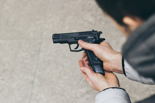 Man with Gun closeup. Human Hand Holding Handgun