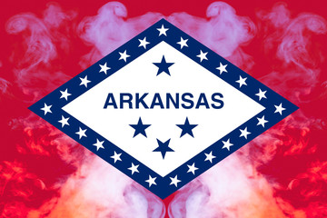 The national flag of the US state Arkansas in against a gray smoke on the day of independence in different colors of blue red and yellow. Political and religious disputes, customs and delivery.