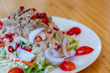 Spicy tuna salad In a white plate, salad this dish consist of tuna, lettuce, chinese cabbage, carrot onion red chilli rough cut, dressing and tomato half cut Used to arrange dishes.