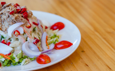 Spicy tuna salad In a white plate, salad this dish consist of tuna, lettuce, chinese cabbage, carrot onion red chilli rough cut, dressing and tomato half cut Used to arrange dishes.