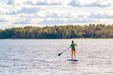 Girl standup paddle boarding. Image of young woman SUP surfing on the lake