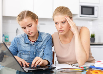 Strict woman supervising study of her daughter