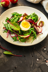 salad with egg, radish, lettuce, arugula, spinach and other leaves (snack). food background. top