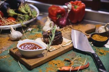 pork steak on wooden board with sauce and vegetables