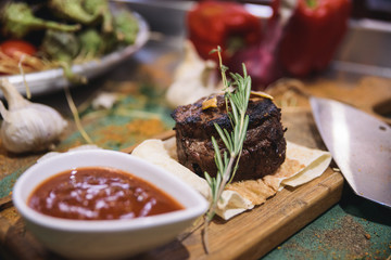 pork steak on wooden board with sauce and vegetables