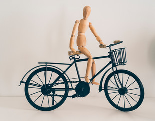 Wooden figure posing in a bicycle, travel and lifestyle.