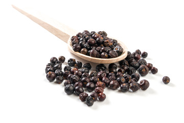 juniper berries on wooden spoon on white background