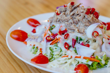 Spicy tuna salad In a white plate, salad this dish consist of tuna, lettuce, chinese cabbage, carrot onion red chilli rough cut, dressing and tomato half cut Used to arrange dishes.