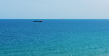 blue sea surface with small ships on the horizon