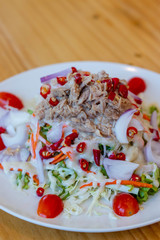 Spicy tuna salad In a white plate, salad this dish consist of tuna, lettuce, chinese cabbage, carrot onion red chilli rough cut, dressing and tomato half cut Used to arrange dishes.