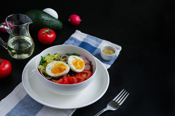 healthy bowl with boiling egg halves tomatoes avocado red onion radish arugula sesame seeds  and ingredients on  black background copy space