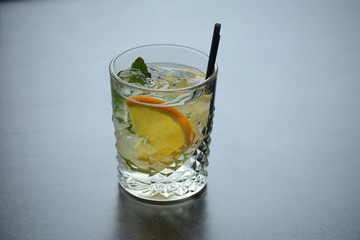 A glass of lemonade with ice and a slice of lemon on a wooden dark table