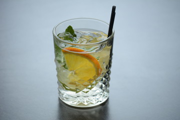 A glass of lemonade with ice and a slice of lemon on a wooden dark table