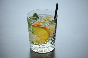 A glass of lemonade with ice and a slice of lemon on a wooden dark table