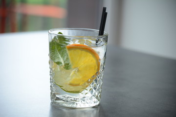 A glass of lemonade with ice and a slice of lemon on a wooden dark table