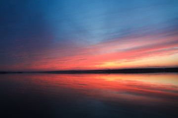 Dramatic sunset sky background with river, fiery clouds, yellow, orange and pink colour, nature background. Beautiful skies