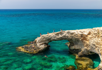 CYPRUS, THE BRIDGE OF LOVERS - MAY 11/2018: Tourists jump from a height into the azure waters of the Mediterranean Sea.