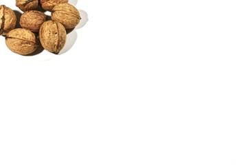 Inshell walnuts. In the upper left corner of the white background. Close-up.