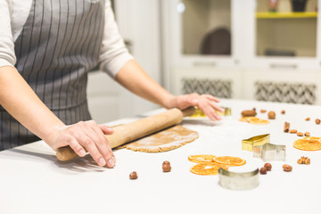 Young pretty woman prepares the dough and bakes gingerbread and cookies in the kitchen. Merry Christmas and Happy New Year.