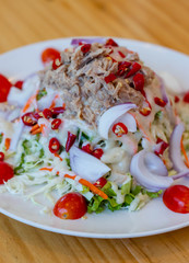 Spicy tuna salad In a white plate, salad this dish consist of tuna, lettuce, chinese cabbage, carrot onion red chilli rough cut, dressing and tomato half cut Used to arrange dishes.
