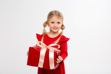 Portrait of little girl in red dress on isolated white background. Smiling Girl in shirt with gifts in hands looking at camera. Isolated gray background. The concept of celebrating, giving and receivi