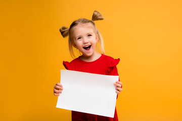 baby girl holding white sheet.Cute little girl with white sheet of paper.yellow background.copy...