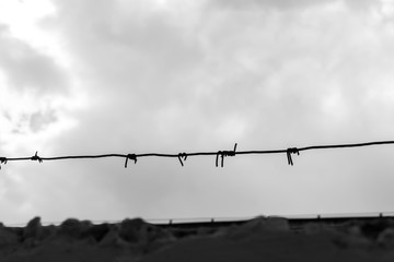 fence with barbed wire against the blue sky. symbol depicting imprisonment in prisons. concept of war and military base.