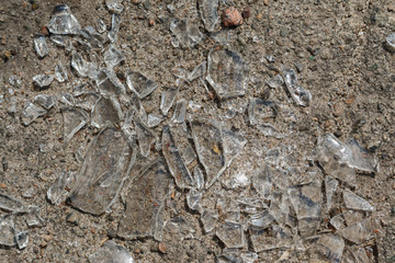 close-up shards of broken car glass on the asphalt road. broken glass on asphalt surface. street vandalism in the city.