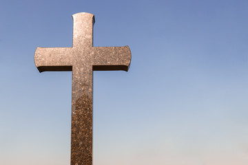 stone cross in a graveyard with copy space for text. crucifix against a blue sky background.
