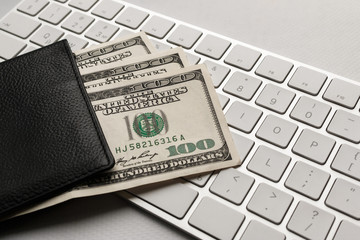 hundred dollar bills in a purse against a white computer keyboard. Fan of one hundred dollar bills in the wallet. purchase of goods and tickets via the Internet.