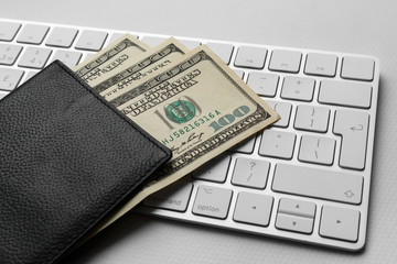 black passport with american banknotes on the white keyboard. passport with dollar bills on the silver keyboard. Fan of one hundred dollar bills in the international passport for travelling.