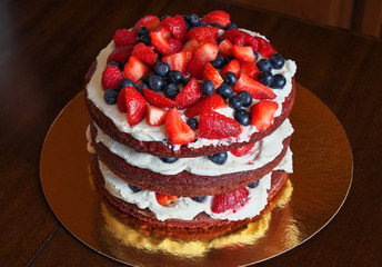 Beautiful delicious red velvet cake with strawberries and blueberries on the table