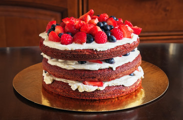 Beautiful delicious red velvet cake with strawberries and blueberries on the table