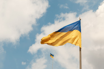 Blue and yellow Ukrainian national flags on a flagpoles against a blue sky, bottom view. The symbol of 2019 ballot and poll in Ukraine.