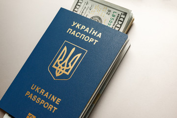 Ukrainian International biometric passport and dollars on the gray steel background. American currency and documents for trip abroad. Migration from Ukraine concept.