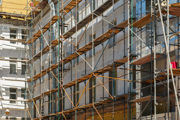 wooden scaffolding with ladders on gray building facade, construction site with framework on buiding.