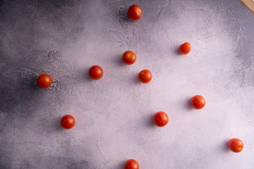 Cherry tomatoes scattered across white textured stone concrete table, top view with copy space. Ingredients for cooking.