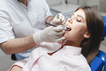 Dental clinic. Reception, examination of the patient. Teeth care. Young woman undergoes a dental examination by a dentist.Happy patient and dentist concept.Female dentist in dental office talking with