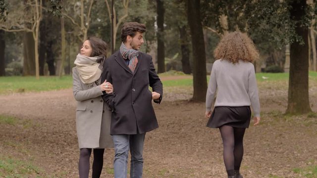 unloyal man walking with his wife and looking other woman's butt