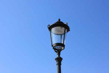 Fototapeta na wymiar Old street lantern isolated on empty blue sky background. Retro lamp close up view