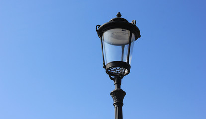 Fototapeta na wymiar Lantern isolated on blue sky background. Classic street lamppost with single light on summer day 
