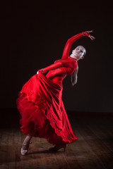 Young hispanic flamenco dancer in red dress isolated on black background