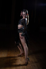 Fototapeta na wymiar Beautiful Latino dancer girl in elegant black dress on black background