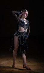Beautiful Latino dancer girl in elegant black dress on black background