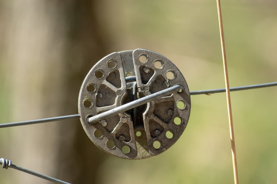 Runder Drahtspanner aus Metall an Zaun vor unscharfem Hintergrund isoliert