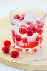 Refreshing drink with raspberries and ice. Lemonade on a white table, vertical orientation